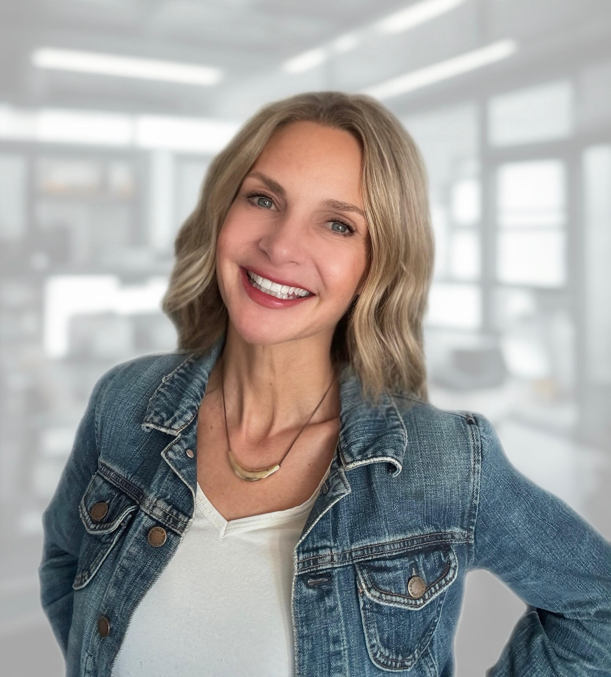 MIchelle Waters, Founder of Waters Edge Co Close-up headshot of blonde-haired woman smiling for the camera. She is wearing a light colored denim jacket.